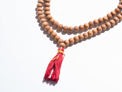 Wooden beaded necklace with a red tassel on a white background