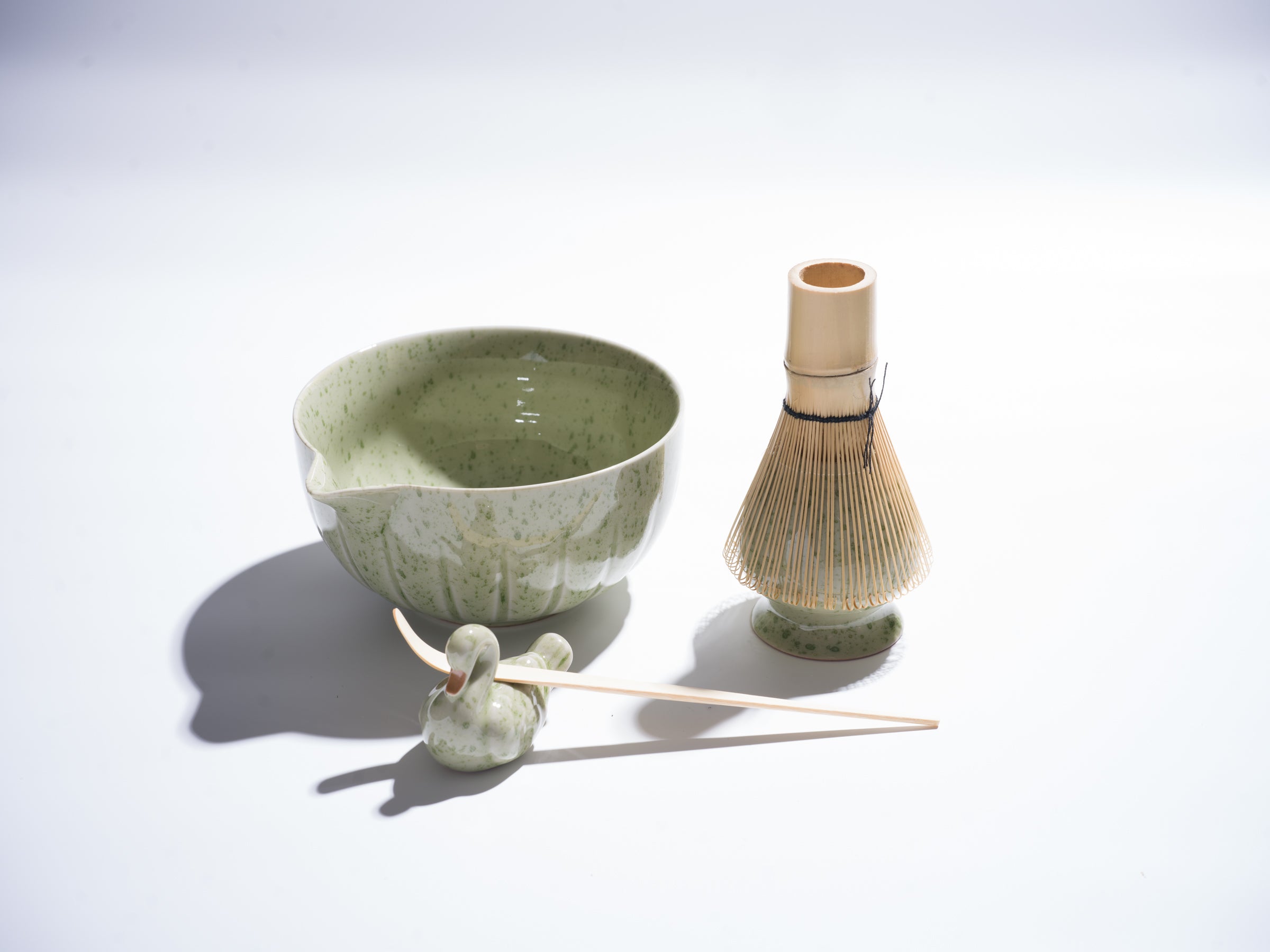 Ceramic tea bowl and whisk set on a light gray background