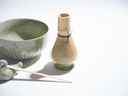 Ceramic bowl, whisk, and other tea-making tools on a light background